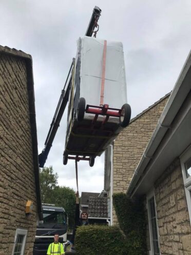 Crane lifting a hot tub over a house near Windlesham, Surrey.