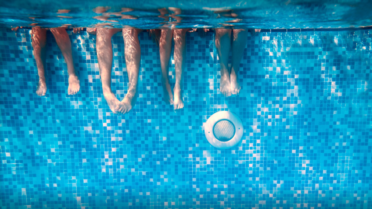 Feet dangling in clear blue swimming pool