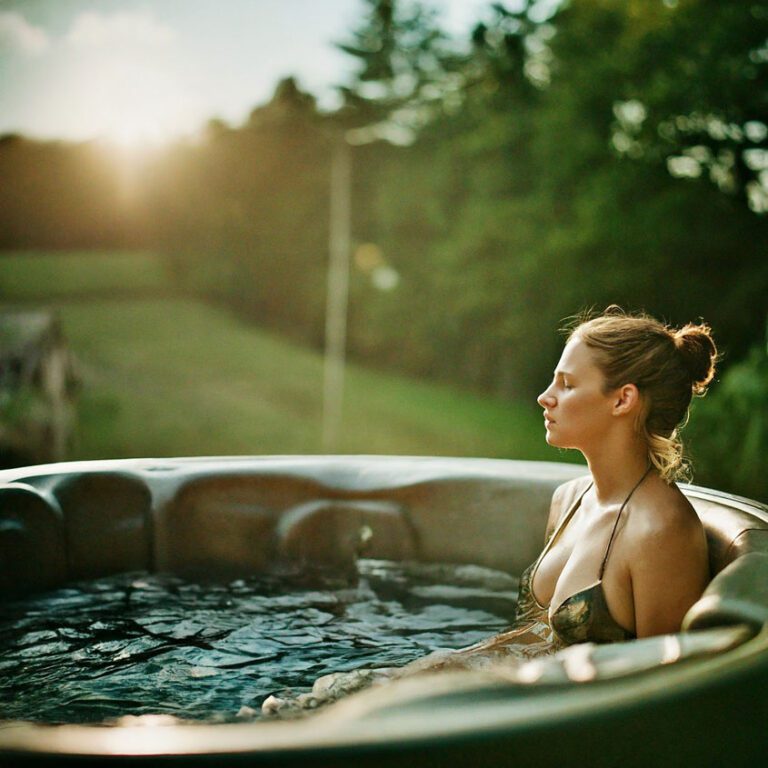 As the evening closes a women smoothes back pain in her hot tub in Surrey UK