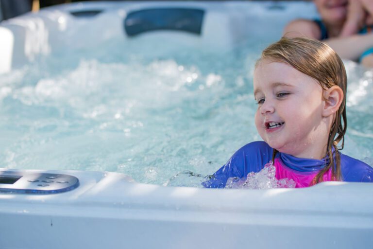 A young child on school holidays enjoys the hot tub bubbles with her mother