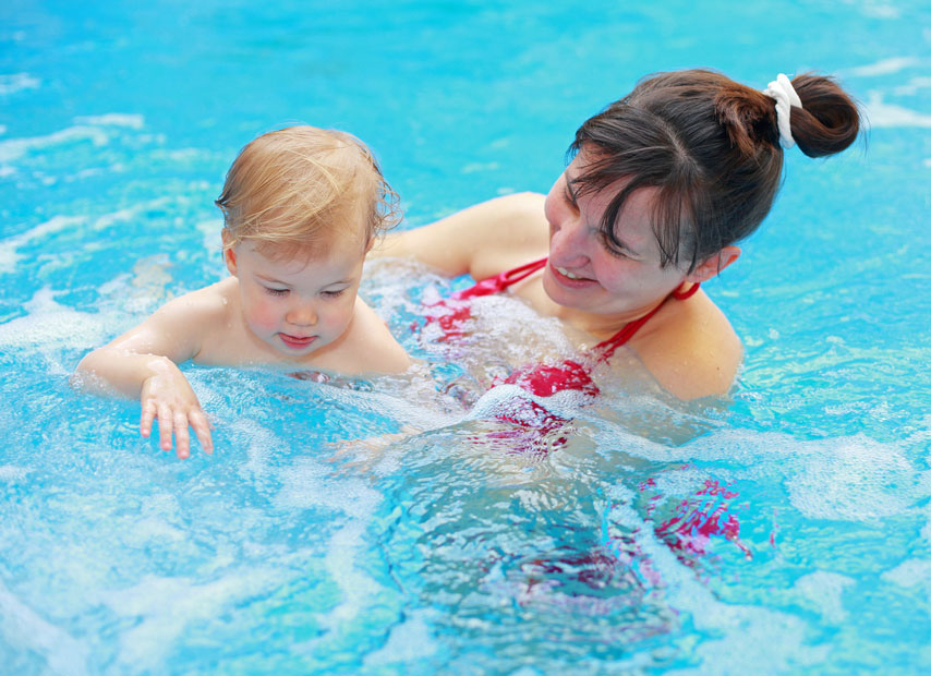 Mum enjoy time with her child in a hot tub, keeping them safe, during an evening in Surrey, UK