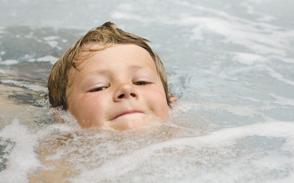 Young boy in a hot tub in Surrey plays in the water safely