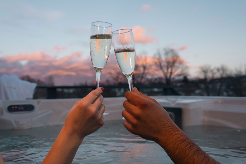 A couple celebrate in a hot tub during Autumn in the UK. They have reviewed the Essential Hot Tub Maintenance Tips in Autumn