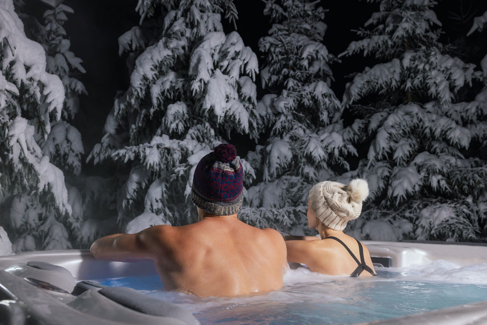 A couple enjoying their hot tub in the winter and being energy efficient with heating